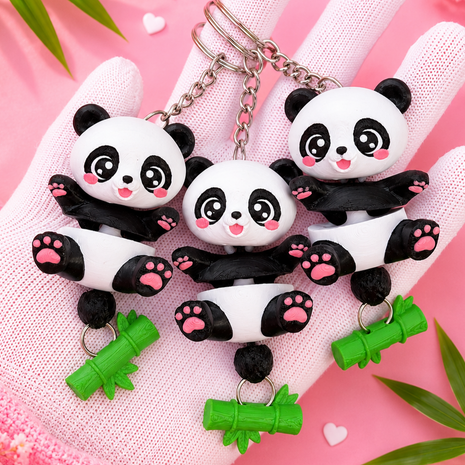 Three Flexi Baby Panda keychains held in a hand with bamboo charms